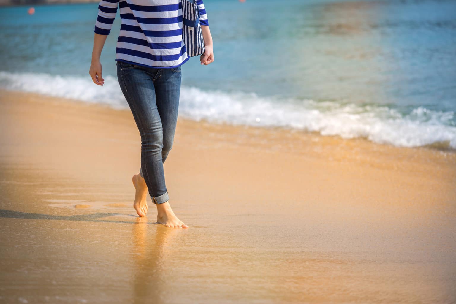 Kvinna går på strand och tänker på sitt kommande ingrepp: fettsugning av venusberg